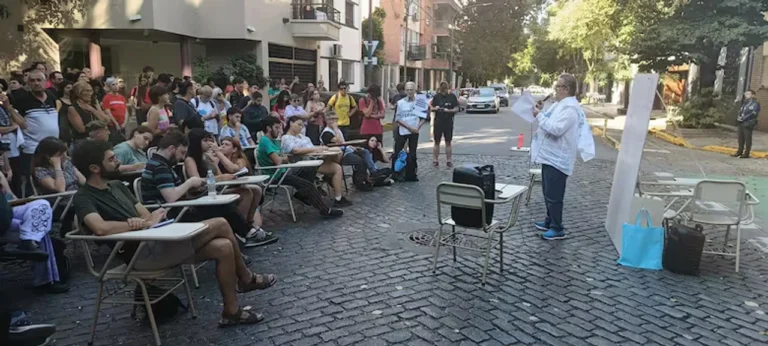 Operativo policial y grupo de personas realizando una clase pública en una calle de Caballito.