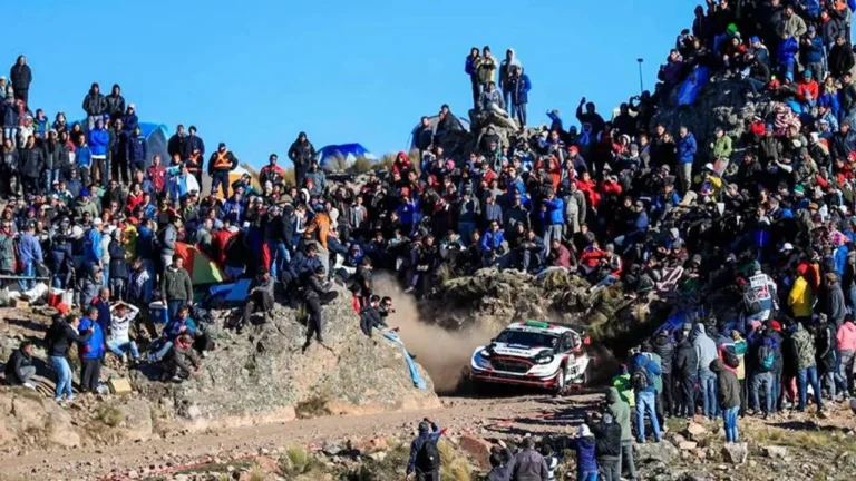 Vehículo de rally accidentado en tramo de tierra, con servicios de emergencia en el lugar.