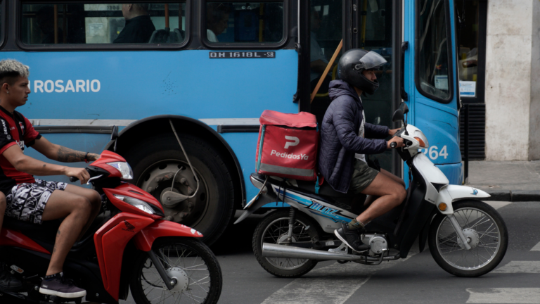 Repartidor de delivery en moto esperando un pedido en una calle de Rosario