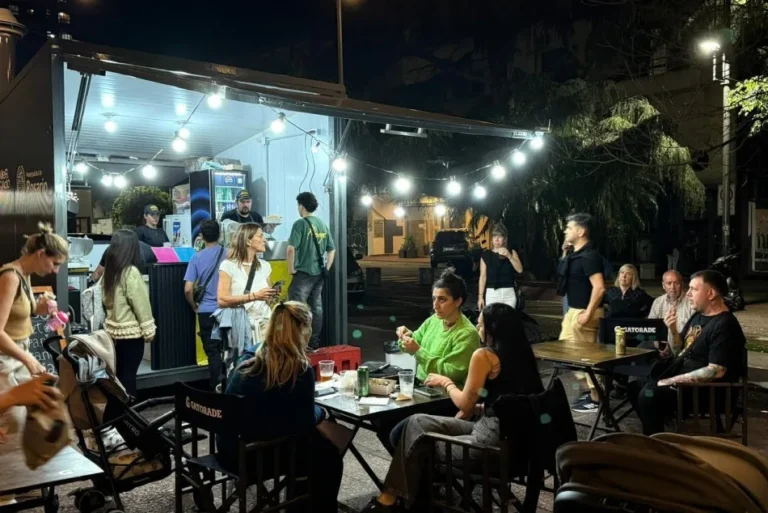 Personas degustando empanadas y disfrutando de la música en vivo en el Mercado del Centro, plaza Montenegro, Santa Fe.